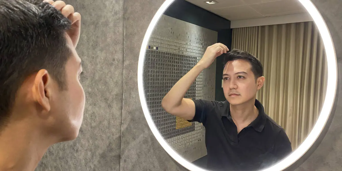 Man looking at hair transplant result in mirror