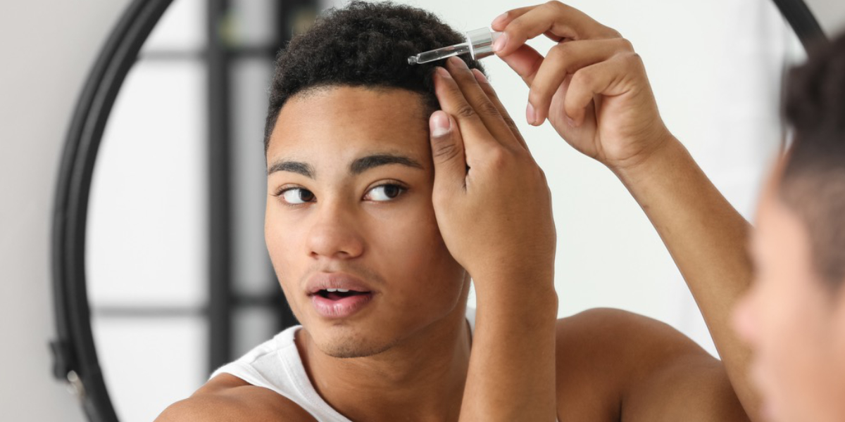 male using either a Minoxidil and Finasteride dropper in front of the mirror